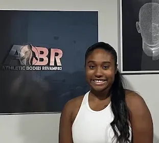 Maya Sharpe, licensed massage therapist, in front of the Athletic Bodies Revamped sign