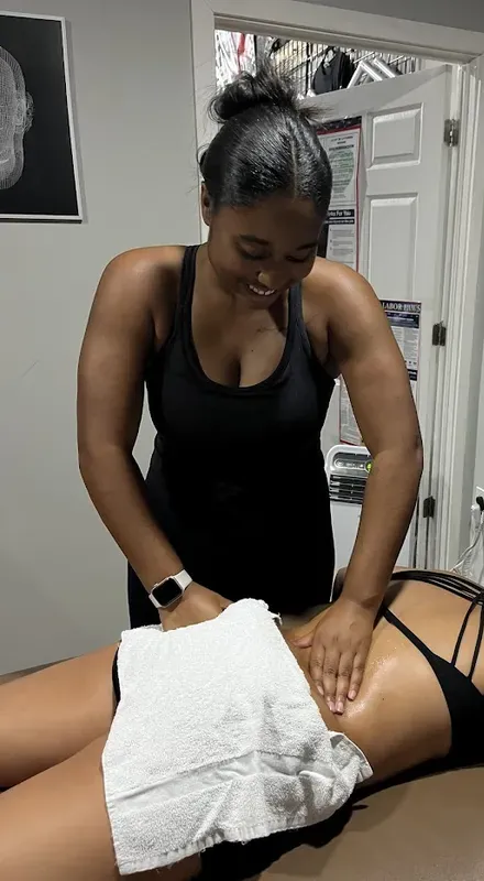 Maya Sharpe smiling as she massages a client's lower back